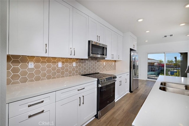 kitchen featuring appliances with stainless steel finishes, a sink, light countertops, dark wood finished floors, and visible vents