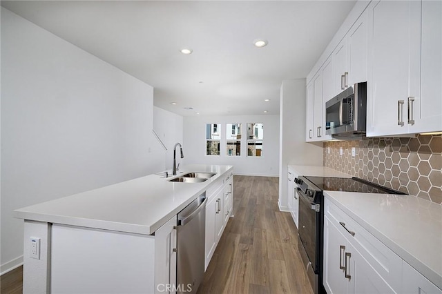 kitchen with tasteful backsplash, wood finished floors, a sink, stainless steel appliances, and white cabinetry