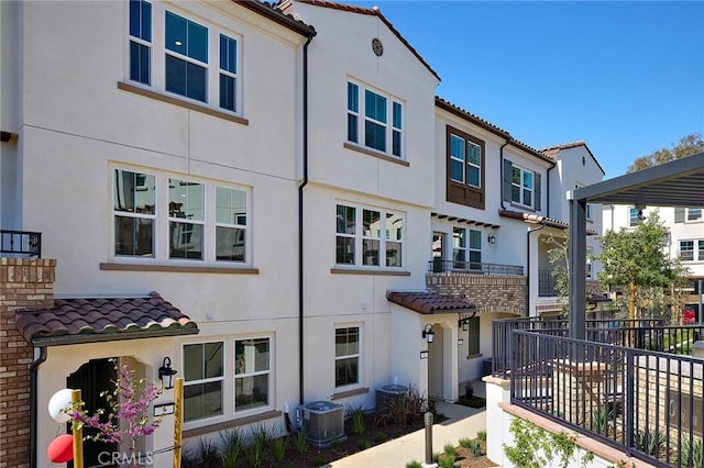 view of front facade featuring a tiled roof, cooling unit, and stucco siding