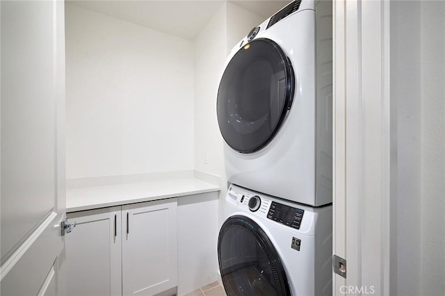 laundry area featuring stacked washer and dryer and cabinet space