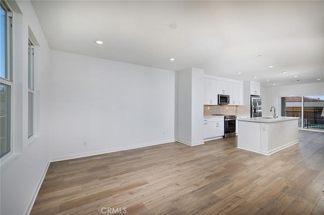 kitchen with light wood-style floors, baseboards, white cabinets, a sink, and stainless steel appliances