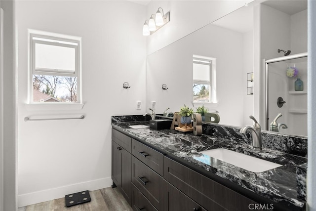 bathroom with a sink, a shower stall, baseboards, and wood finished floors