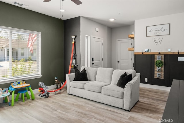 living area with ceiling fan, light wood-type flooring, visible vents, and baseboards