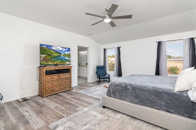 bedroom with lofted ceiling, connected bathroom, multiple windows, and wood finished floors