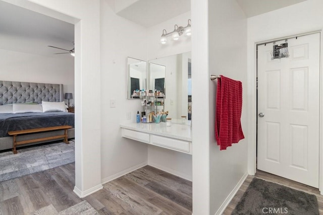 ensuite bathroom featuring ensuite bath, wood finished floors, a ceiling fan, and baseboards