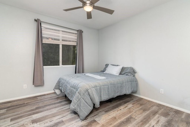 bedroom with wood finished floors, a ceiling fan, and baseboards