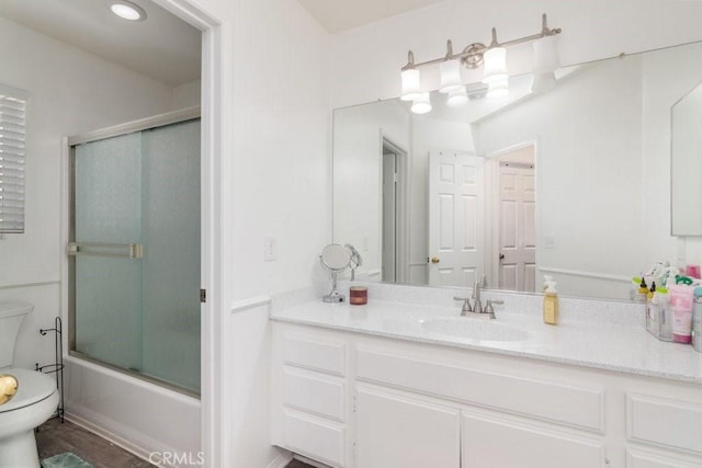 bathroom featuring enclosed tub / shower combo, vanity, and toilet