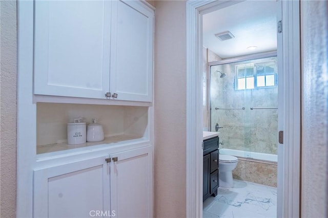 bathroom featuring vanity, visible vents, bath / shower combo with glass door, toilet, and marble finish floor