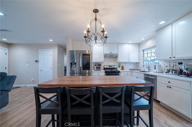 kitchen with tasteful backsplash, white cabinets, stainless steel appliances, and a sink