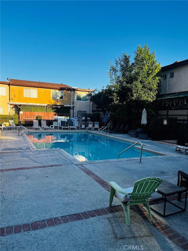 pool with a patio area and fence