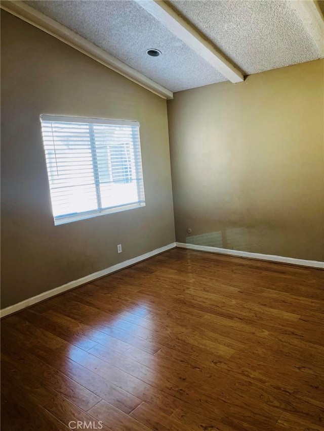 spare room with vaulted ceiling, a textured ceiling, baseboards, and wood finished floors