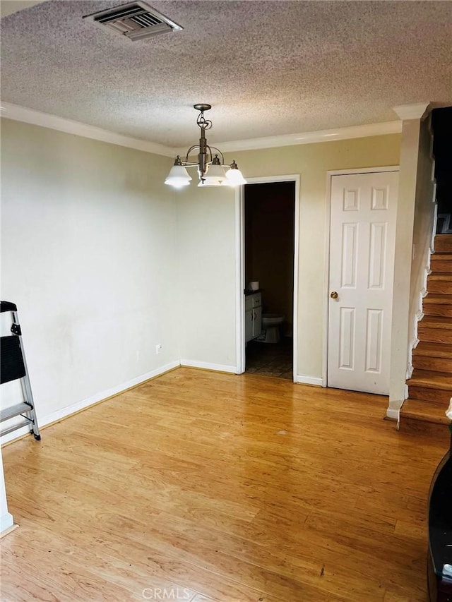 unfurnished dining area with light wood-style floors, visible vents, ornamental molding, and stairway