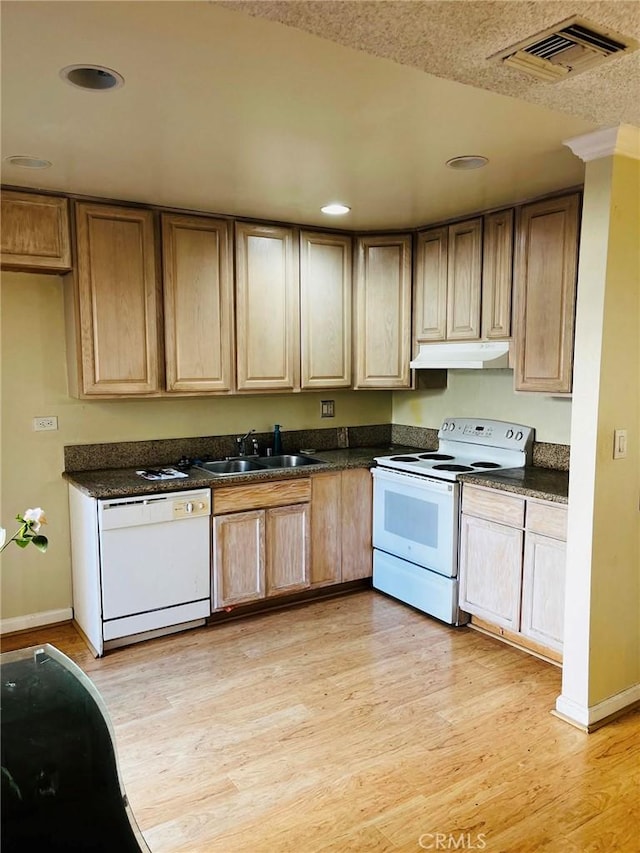 kitchen featuring white appliances, visible vents, dark countertops, under cabinet range hood, and a sink