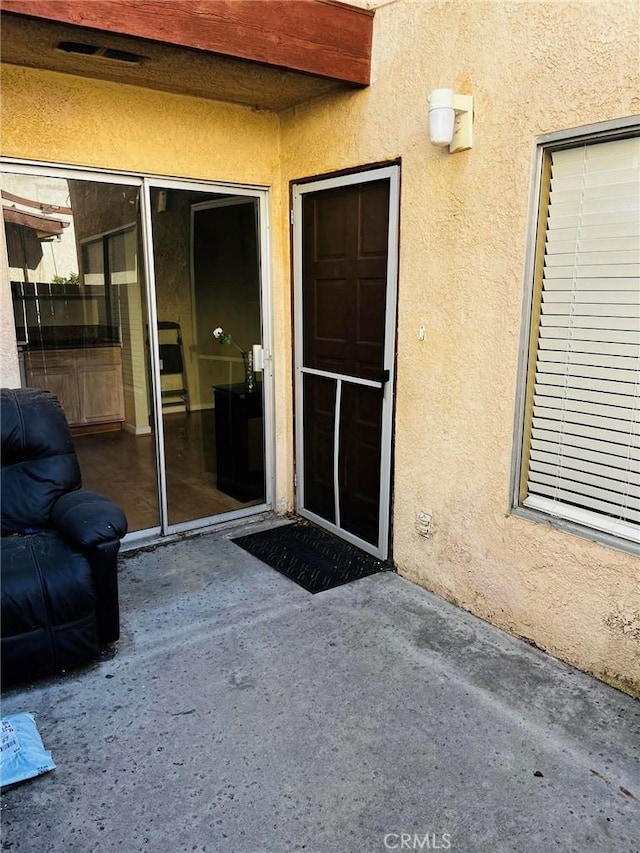 entrance to property featuring a patio area and stucco siding