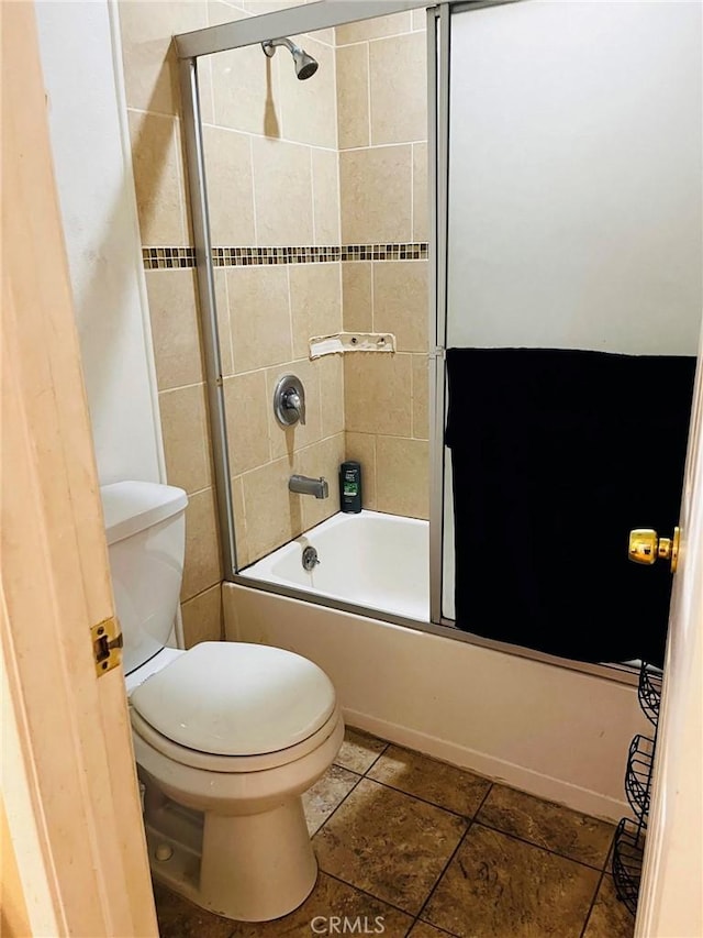 bathroom with toilet, tile patterned flooring, and bath / shower combo with glass door