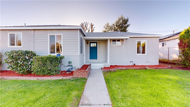 view of front of home featuring crawl space, stucco siding, a front lawn, and fence