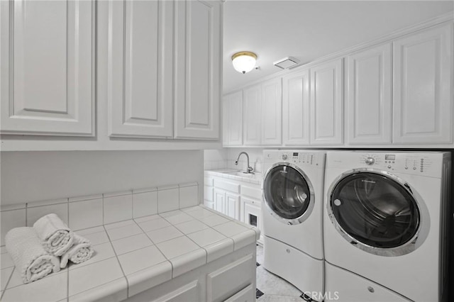 washroom with washing machine and dryer, cabinet space, and a sink