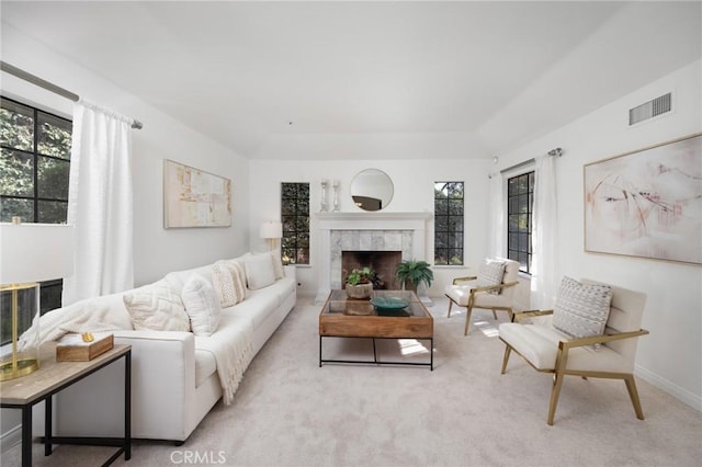 living room featuring carpet floors, a tile fireplace, visible vents, and baseboards