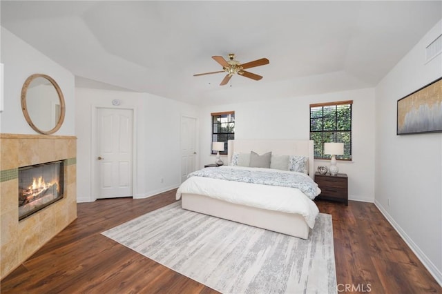 bedroom featuring a tile fireplace, dark wood-style flooring, and multiple windows