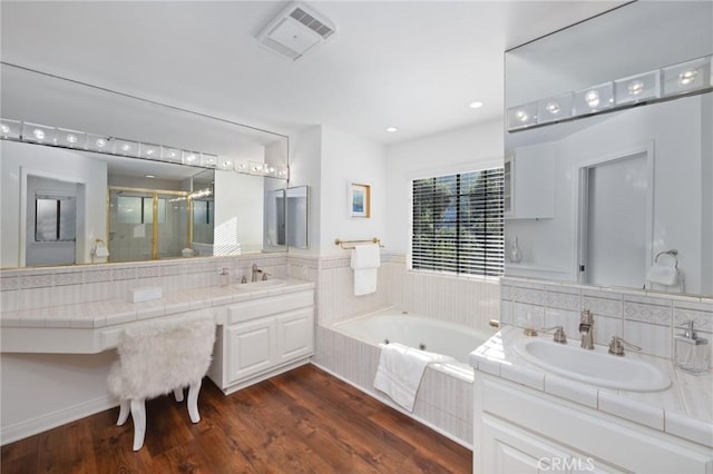 full bath with a stall shower, wood finished floors, visible vents, and a jetted tub