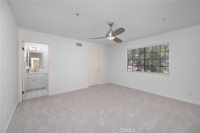 unfurnished bedroom featuring ensuite bath, carpet flooring, visible vents, and baseboards