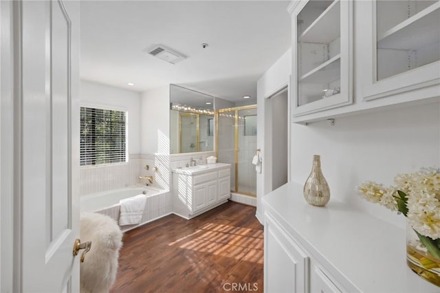 full bath with a garden tub, wood finished floors, visible vents, vanity, and a shower stall