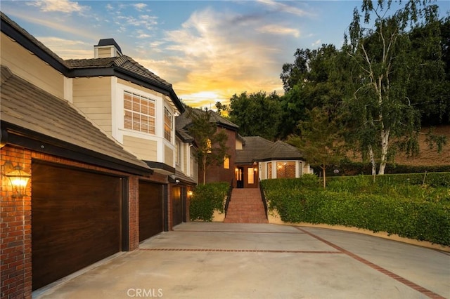 view of front of property featuring driveway, an attached garage, and brick siding