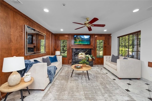 living area featuring wooden walls, a premium fireplace, a ceiling fan, and recessed lighting