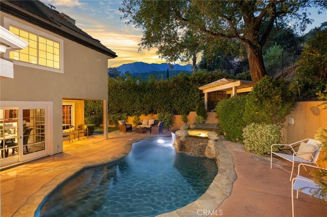 pool at dusk featuring a mountain view and a patio