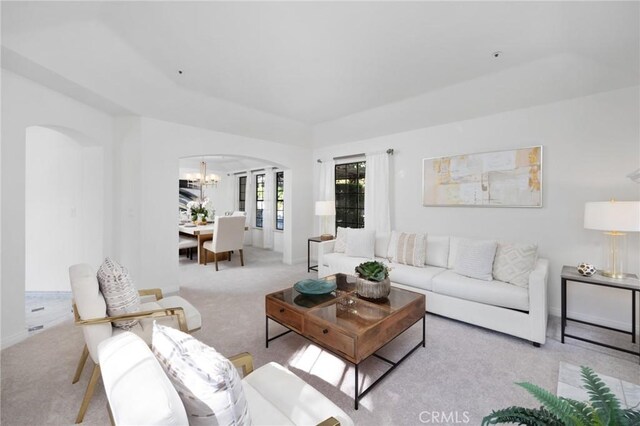 living area featuring arched walkways, carpet flooring, and a chandelier