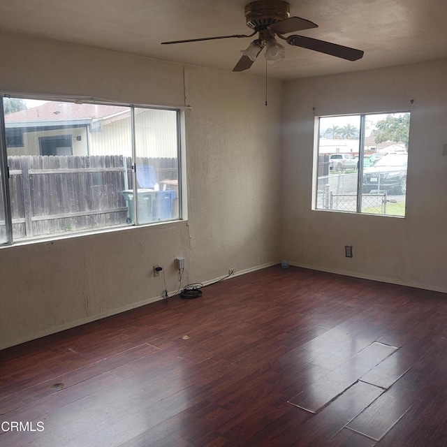 empty room featuring baseboards, a ceiling fan, and wood finished floors