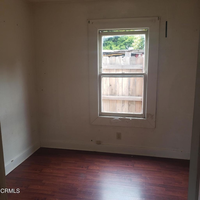 unfurnished room with dark wood-type flooring and baseboards