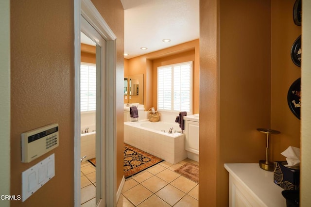 full bath with a wealth of natural light, tile patterned flooring, a garden tub, and a textured wall