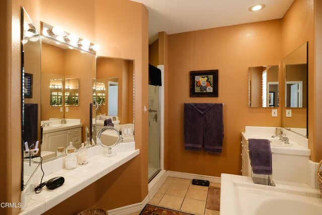 bathroom with baseboards, a garden tub, tile patterned flooring, a shower stall, and two vanities