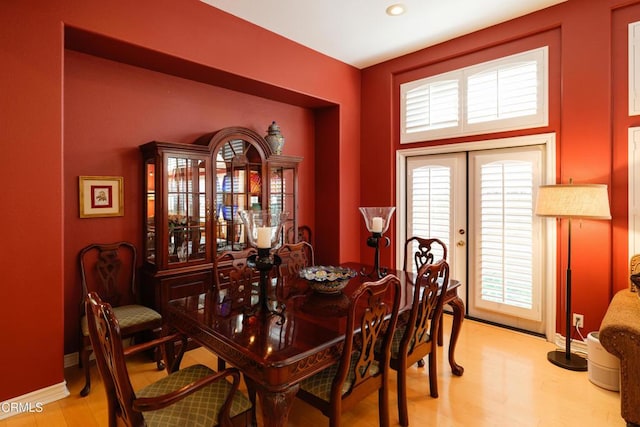 dining area with light wood-style flooring, baseboards, and french doors