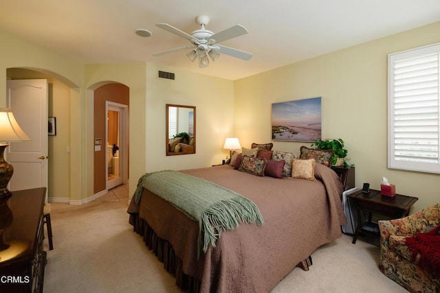 bedroom with arched walkways, visible vents, ceiling fan, and light carpet