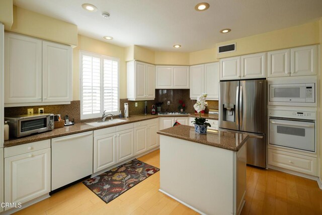 kitchen with light wood finished floors, visible vents, a sink, stainless steel appliances, and backsplash