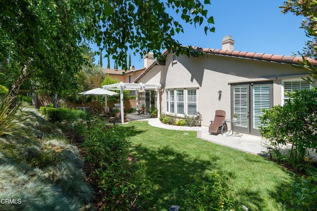 back of house with a lawn, a chimney, a patio area, a pergola, and stucco siding