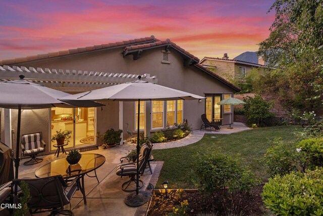 rear view of property with a patio, a lawn, stucco siding, and a pergola