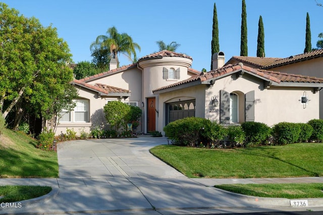 mediterranean / spanish home featuring a front yard, a chimney, an attached garage, and stucco siding