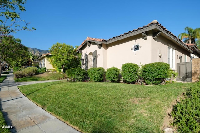 view of home's exterior featuring a lawn, a tile roof, and stucco siding