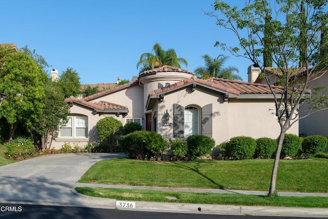 mediterranean / spanish house featuring a tile roof, a front lawn, concrete driveway, and stucco siding