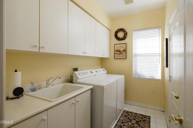 washroom with cabinet space, visible vents, a sink, washer and dryer, and baseboards