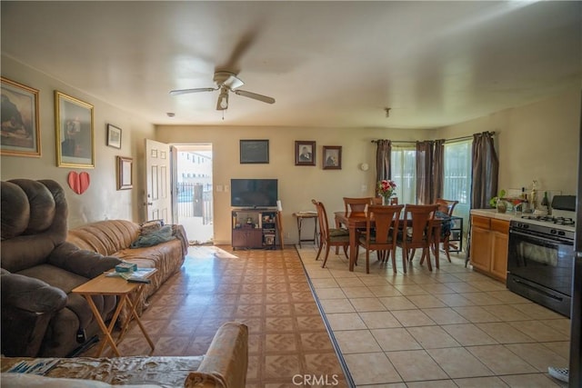 living area with a ceiling fan and light tile patterned floors