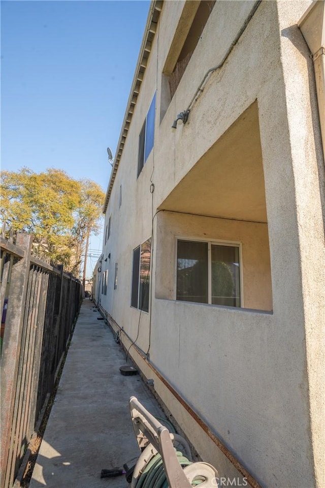 view of side of property with fence and stucco siding