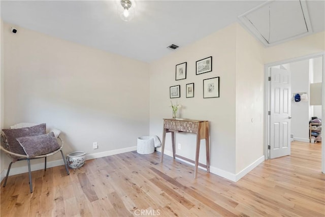 sitting room featuring attic access, baseboards, and wood finished floors