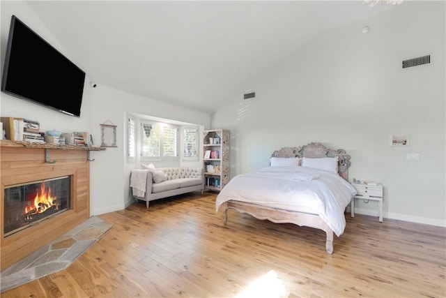 bedroom featuring light wood finished floors, a fireplace with flush hearth, visible vents, and baseboards