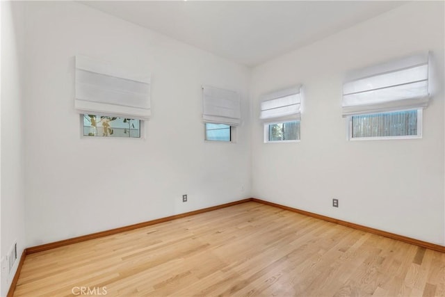 spare room with baseboards and wood finished floors