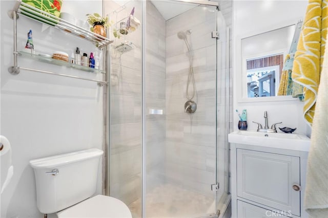 bathroom featuring a shower stall, toilet, and vanity
