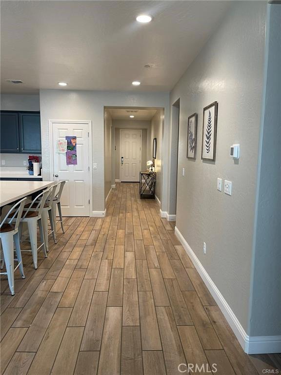 hall with baseboards, wood finished floors, and recessed lighting